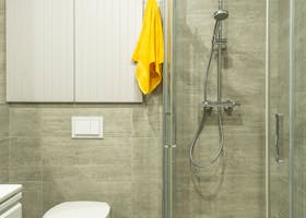Bright modern bathroom featuring a shower cabin, toilet, and yellow towel for a clean look.